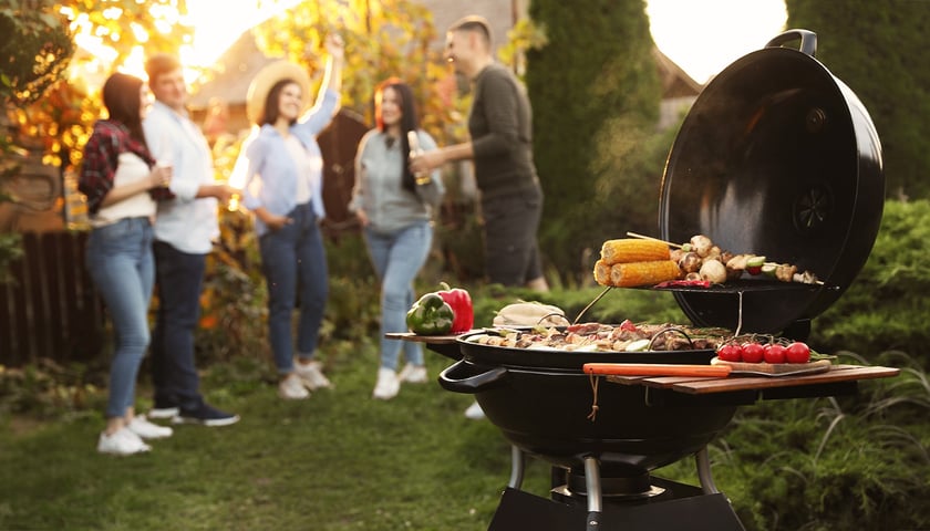Grill z potrawami. Na zdjęciu uśmiechnięci ludzie 