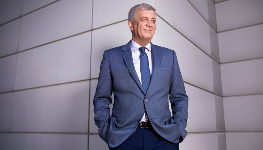 Mężczyzna w marynarce stojący na tle ściany - prof. Jarosław Bosy, dyrektor Łukasiewicz – PORT.