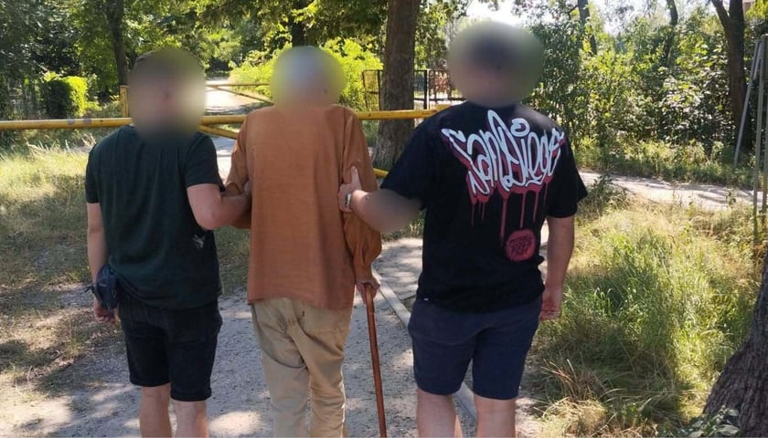 dwóch mężczyzn (policjanci w cywilnych ubraniach) prowadzi starszego mężczyznę