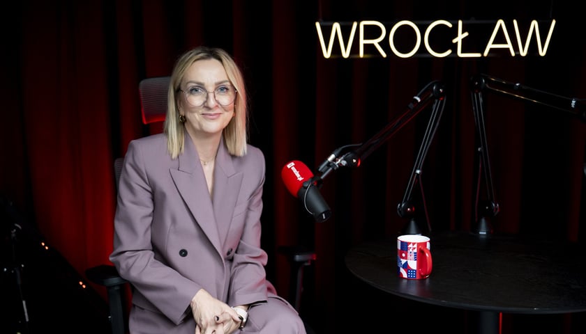 Kobieta w okularach i garsonce siedząca w studiu przy mikrofonie - Paulina Tyniec-Piszcz, dyrektor Departamentu Infrastruktury i Transportu Urzędu Miejskiego Wrocławia.