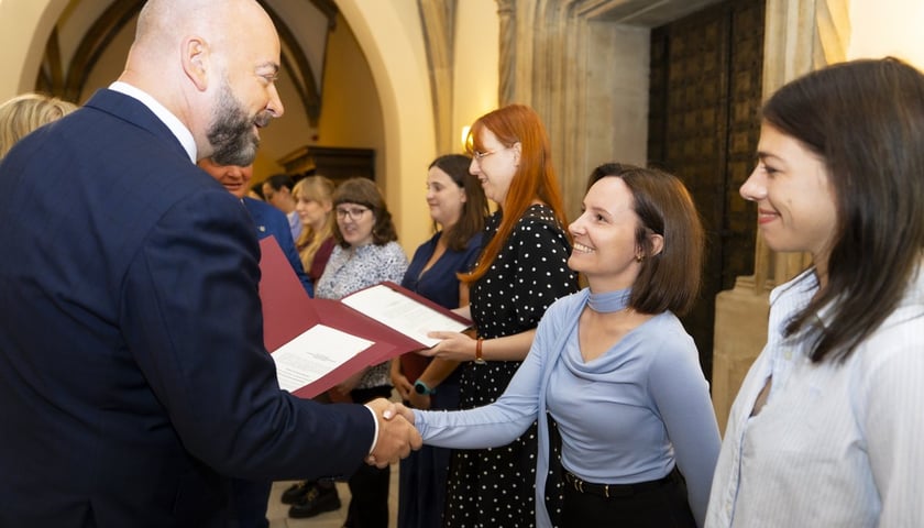 Uroczystość wręczenia aktów na stopień nauczyciela mianowanego we Wrocławiu, 26 sierpnia 2026 z udziałem prezydenta Wrocławia Jacka Sutryka. Na zdjęciu prezydent wręcza dokument uśmiechniętej nauczycielce.