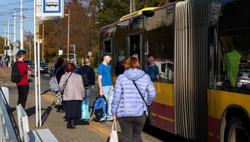 Zdjęcie ilustracyjne - pasażerowie wsiadają do autobusu na przystanku.