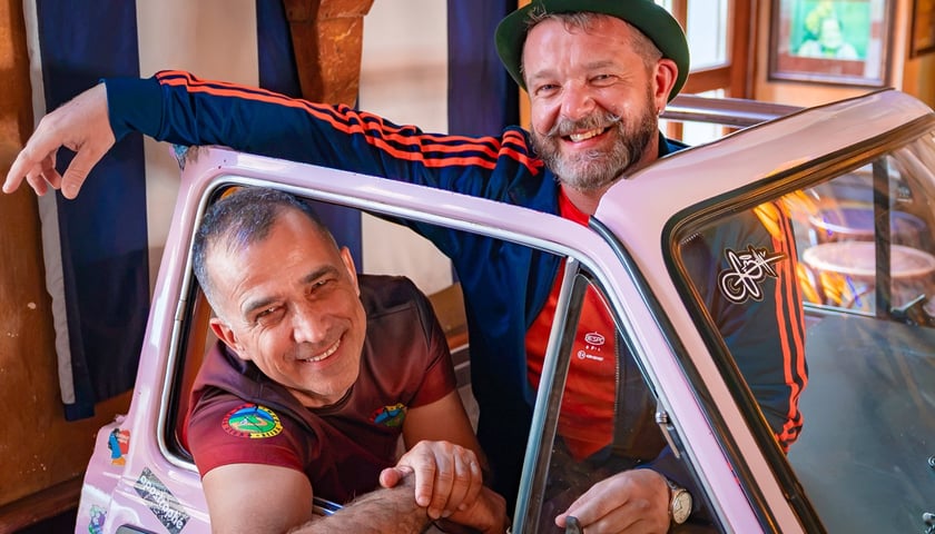 Dwóch przodowników PTTK - Jan Kozdrowski i Grzegorz Grzeszczyk, pozują do zdjęcia w zabytkowym samochodzie