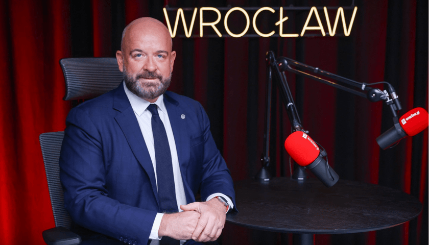 Jacek Sutryk, prezydent Wrocławia  siedzi w granatowym garniturze w studio wroclaw.pl przy mikrofonie