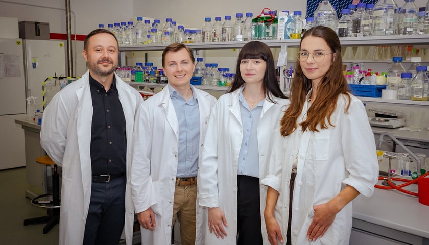 Prof. Łukasz Opaliński, doktoranci Aleksandra Chorążewska i Krzysztof Ciura oraz dr Natalia Porębska. Na zdjęciu czworo ludzi w białych strojach w laboratorium
