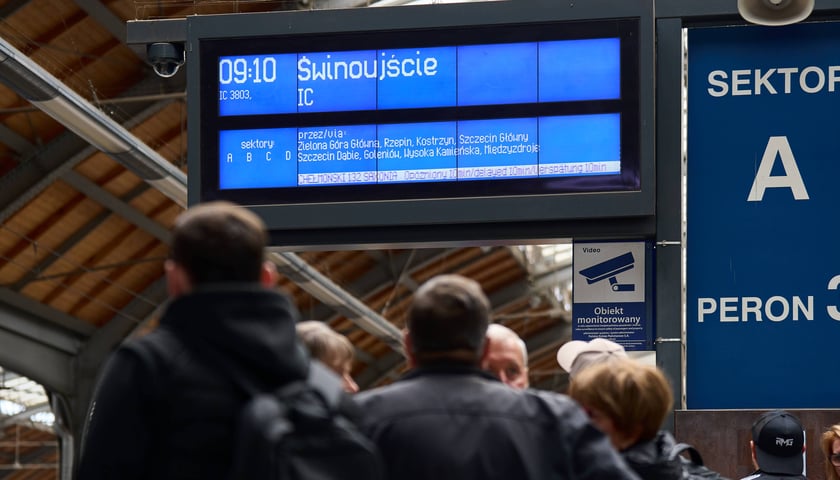 Pasażerowie pod tablicą informującą o opóźnionym pociągu IC Chełmoński do Świnoujścia, Wrocław Główny, 11 września 2026