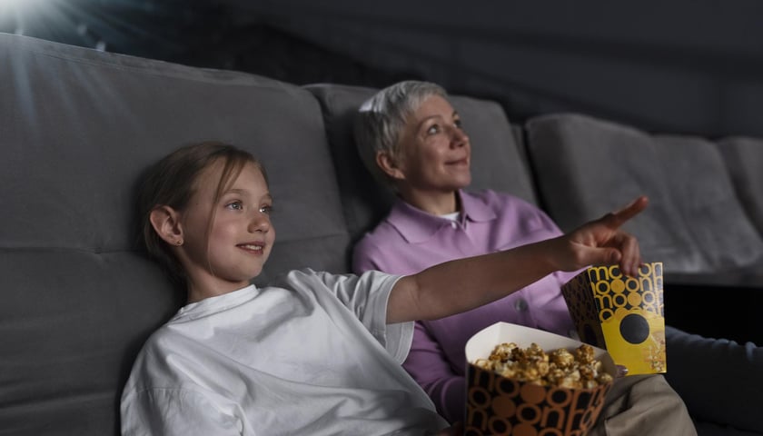Zdjęcie ilustracyjne. Starsza kobieta i dziewczynka oglądają film w kinie.