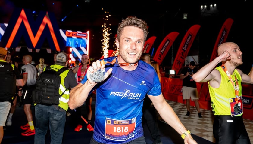 Biegacz Marcin (z numerem startowym 1818) z medalem na mecie 12. Tarczyński Nocnego Wrocław Półmaratonu, 6 czerwca 2026