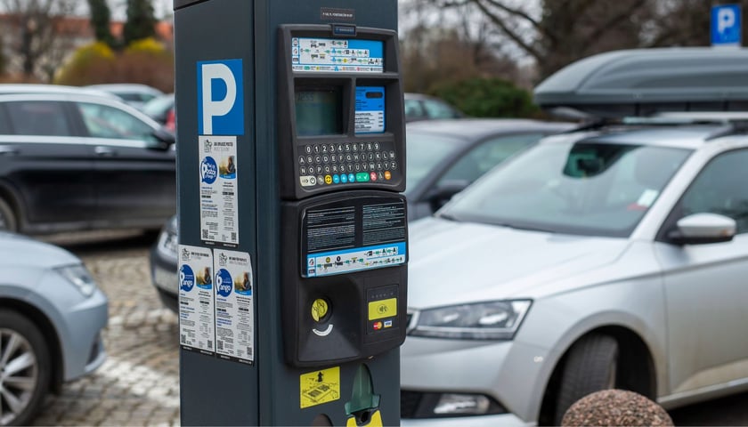 zdjęcie ilustracyjne: parkomat do przyjmowania opłat, w tle zaparkowane samochody