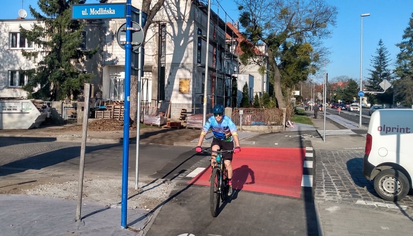 Świeżo pomalowany na czerwono przejazd rowerowy przy skrzyżowaniu ulic Modlińskiej i Racławickiej. 