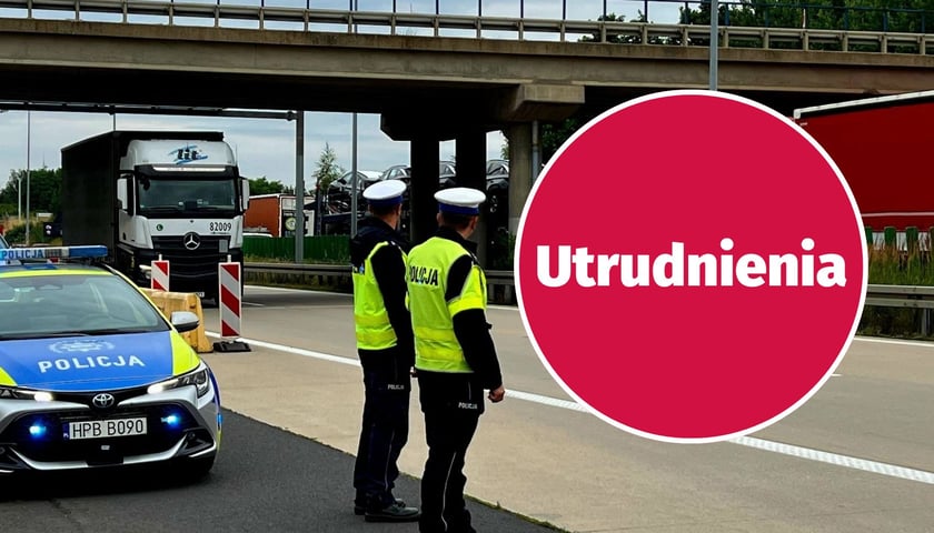 Radiowóz i dwóch policjantów na autostradzie pod wiaduktem, w tle ciężarówki zatrzymane na pasie; na zdjęciu czerwone kółko z napisem "Utrudnienia", zdjęcie ilustracyjne. A4 pod Wrocławiem: zamknięcia łącznic w Kątach Wrocławskich i Budziszowie