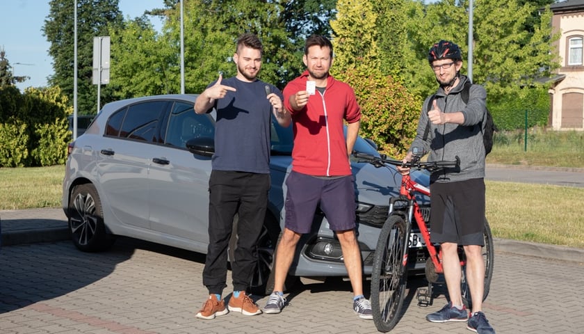 Początek testu. Parking obok przystanku kolejowego Bielany Wrocławskie, 14 czerwca, godz. 6.55 rano. Od lewej stoją: Adam z kluczykami do auta, Michał z biletem kolejowym i Leszek z rowerem.