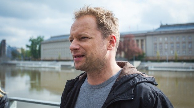 Maciej Stuhr w scenie pod budynkiem Biblioteki Uniwersyteckiej z widokiem na Urząd Wojewódzki