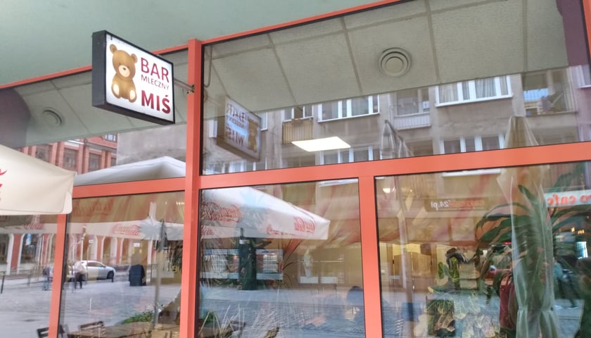Na zdjęciu Bar Miś widok z ulicy: szklana witryna i szyld z misiem i napisem Bar Miś