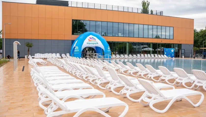 Na zdjęciu budynek aquaparku  z zewnątrz, na pierwszym planie puste białe fotele