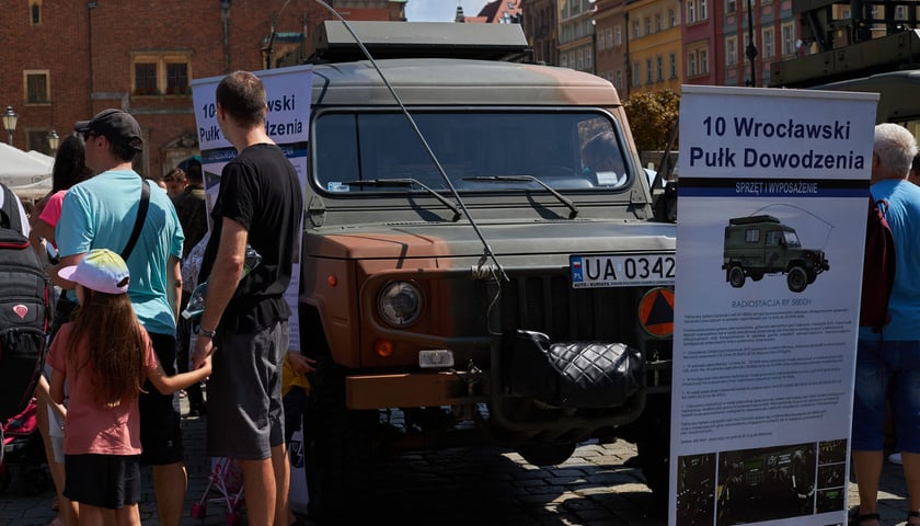 na zdjęciu samochód wojskowy na wrocławskim Rynku podczas prezentacji oraz plansza informacyjna 10. Wrocławskiego Pułku Dowodzenia