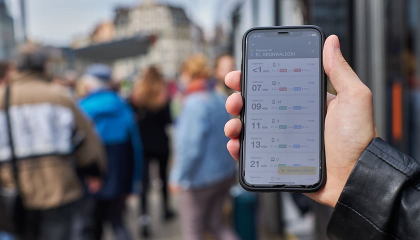 Na zdjęciu telefon z włączoną aplikacją JakDojadę, za pośrednictwem której można kupić bilety wrocławskiej komunikacji miejskiej