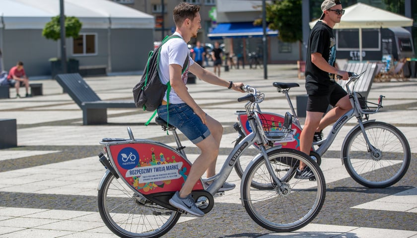 Na zdjęciu dwie osoby na pl. Nowy Targ jadące na rowerach wypożyczonych w sieci Wrocławskiego Roweru Miejskiego