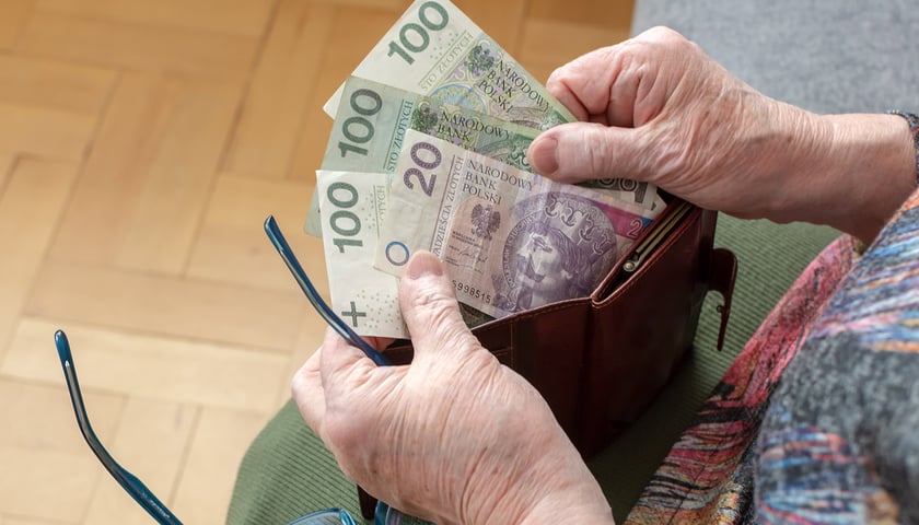 Na zdjęciu starsza kobieta trzyma w rękach portmonetkę i banknoty