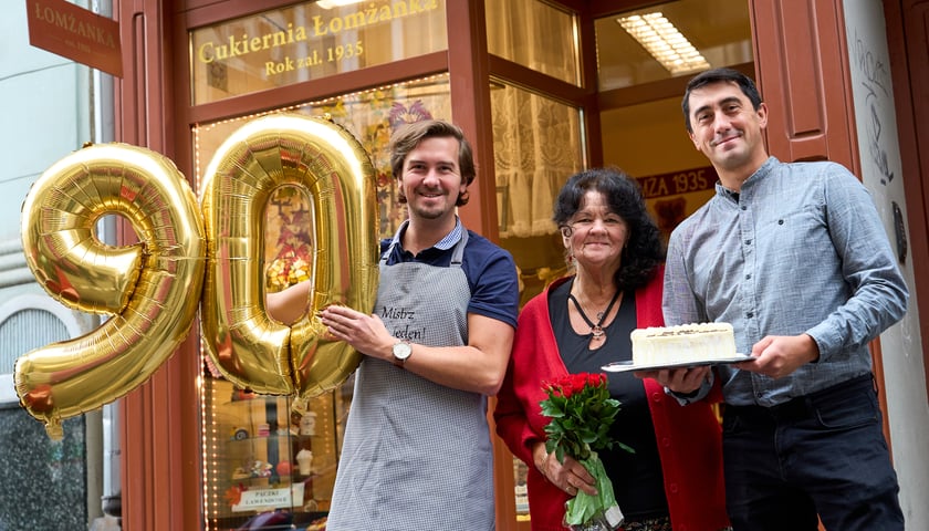 Michał i Paweł Wojczyńscy, wnuki założycieli Łomżanki oraz ich mama przed cukiernią przy ul. Ruskiej. Trzymają balony z cyfrą 90 oraz tort