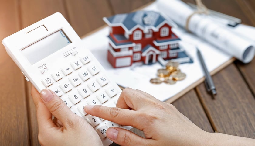 Na zdjęciu kalkulator i osoba licząca wysokość raty kredytu hipotecznego / zdjęcie ilustracyjne