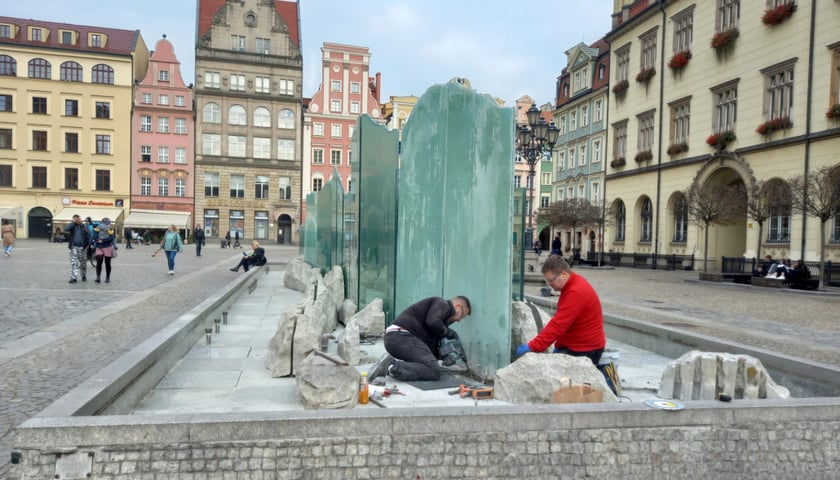 Na zdjęciu: dwójka mężczyzn naprawia fontannę Zdrój na placu Gołębim w Rynku