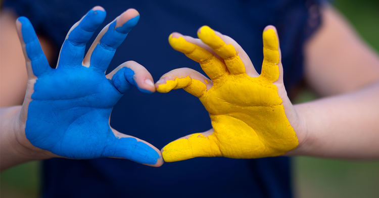 na zdjęciu dwie dłonie: jedna pomalowana na niebiesko, druga - na złot. Razem tworzą felgę Ukrainy