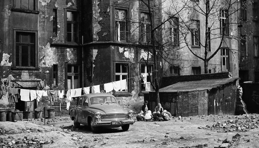 Ulica Lwowska, rok 1961. Na podwórku stoi samochód, wisi na sznurku pranie, obok bawią się dzieci