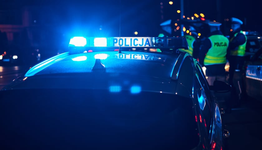 Na zdjęciu radiowóz policyjny i funkcjonariusze policji. Zdjęcie ilustracyjne