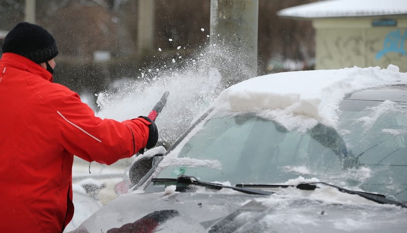 Na zdjęciu zima we Wrocławiu, mężczyzna odśnieżający swój samochód / zdjęcie ilustracyjne
