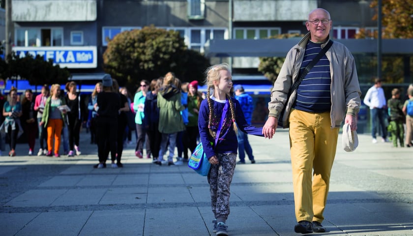 Na zdjęciu mężczyzna w sile wieku spacerujący z wnuczką. Zdjęcie ilustracyjne