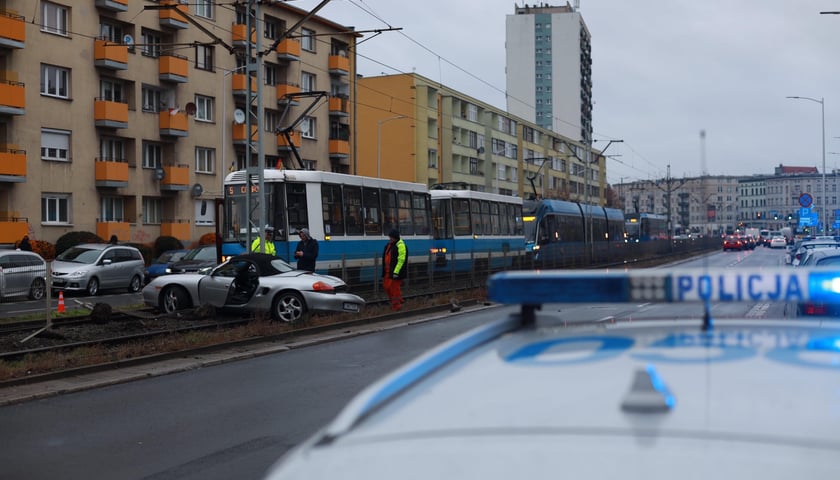 na zdjęciu samochód na torowisku blokuje przejazd tramwajów, na pierwszym planie radiowóz policyjny, w tle "korek" tramwajów
