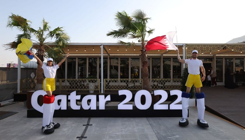 Na zdjęciu kobieta i mężczyzna z flagami Ekwadoru i Kataru oraz napis Qatar 2022 