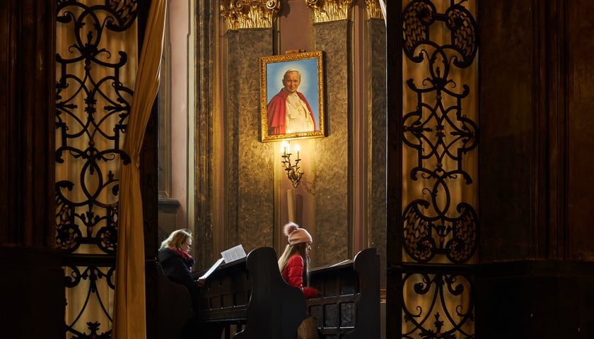 Na zdjęciu dwie kobiety, które modlą się we wnętrzu kościoła