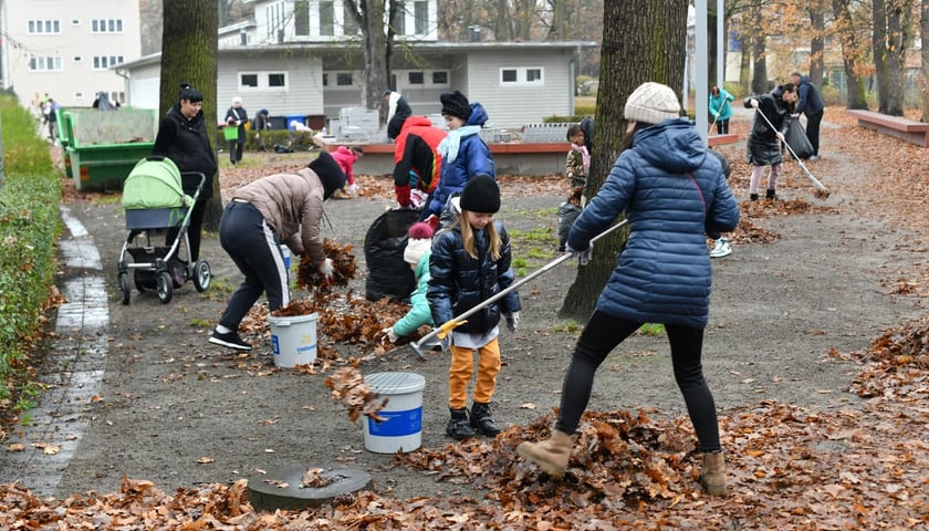 Na zdjęciu grupa dzieci i dorosłych sprzątających liście na osiedlu WuWa we Wrocławiu