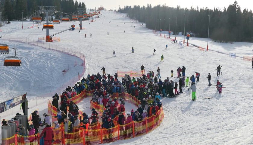 Na zdjęciu ośnieżony stok narciarski z narciarzami, którzy czekają w kolejce do wyciągu. Zdjęcie ilustracyjne 