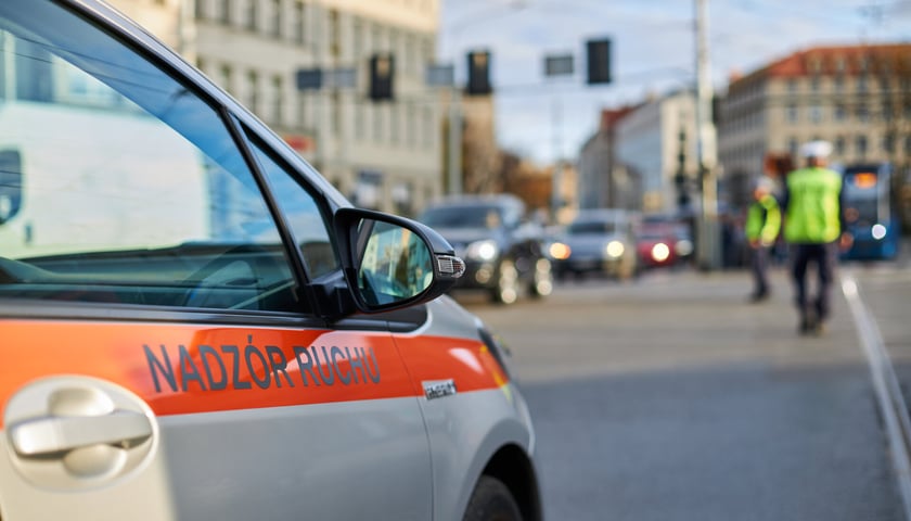 na zdjęciu samochód z napisem nadzór ruchu MPK, w tle policja kieruje ruchem, zdjęcie ilustracyjne