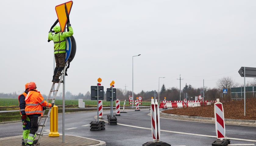 Na zdjęciu: robotnicy odsłaniający znak drogowy na nowym rondzie w ulicy Grota-Roweckiego