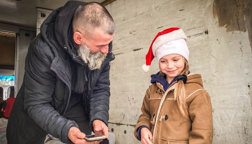 Mikołaj z Kramatorska. Donbas, grudzień 2022. Na zdjęciu starszy mężczyzna z małą dziewczynką.