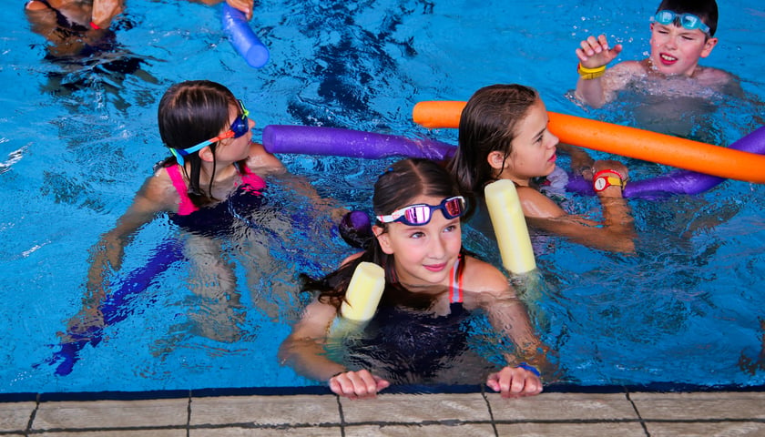 Na zdjęciu dzieci pływają w basenie