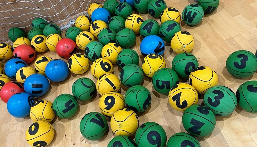 Różnokolorowe piłki EDUball rozrzucone na podłodze.