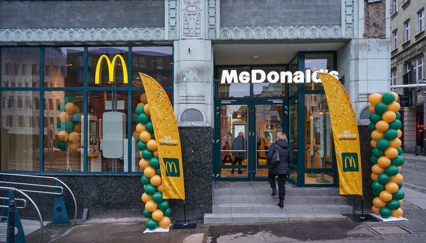 Na zdjęciu kobieta wchodząca do nowo otwartego McDonald'sa przy ul. Ruskiej, w zabytkowym budynku dawnego Domu Towarowego Maxa Goldsteina „Reussenhof” 