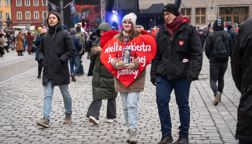 Na zdjęciu koncert WOŚP na wrocławskim Rynku oraz wolontariuszka przebrana za wielkie czerwone serce z napisem "Wielka Orkiestra Świątecznej Pomocy"