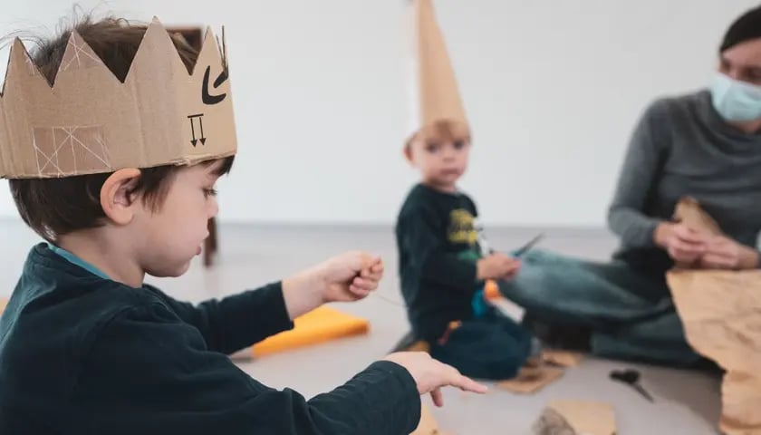 Na zdjeciu dzieci w koronach z kartonu, bawiące się wycinankami, uczestniczące w projekcie "Sobotnie teatranki" - Mikrogranty 2021. Zdjęcie ilustracyjne.