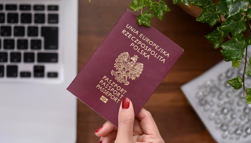 Na zdjęciu polski paszport w kobiecej dłoni