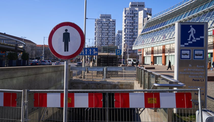 Barierki i znak przed zamkniętym zejściem do przejścia podziemnego przy Pasażu Grunwaldzkim. Zdjęcie zrobione w lutym 2023 r.