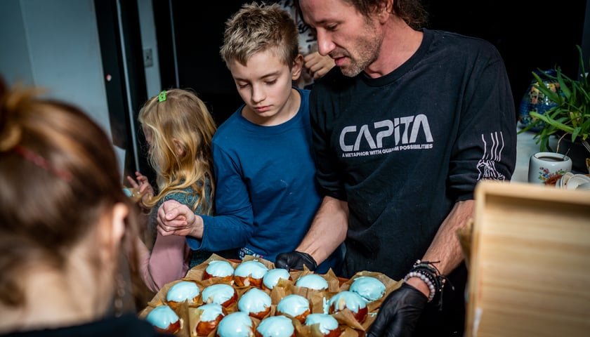 Na zdjęciu: kucharz Mateusz Zielonka rozdaje błękitne pączki dzieciom 