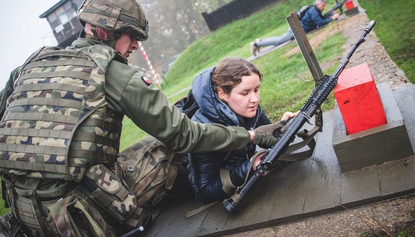Na zdjęciu widać żołnierza WP w mundurze i kobietę z karabinem w rękach