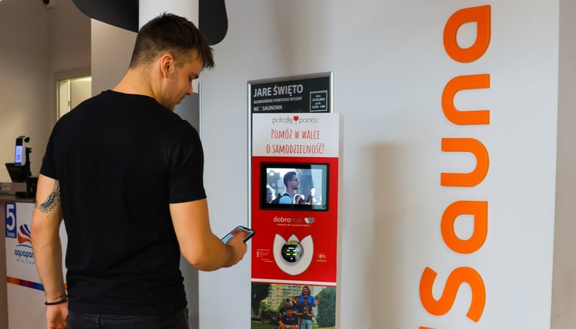 Na zdjęciu mężczyzna korzystający z "Dobromatu" - przypominającego bankomat urządzenia, pozwalającego wpłacić charytatywny datek.