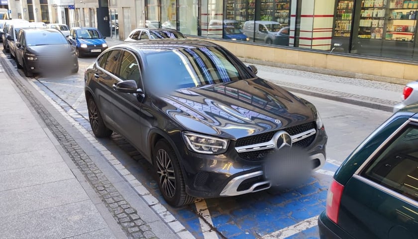 Na zdjęciu grafitowy mercedes zaparkowany bezprawnie na kopercie dla osób z niepełnosprawnościami przy ul. Łaciarskiej we Wrocławiu